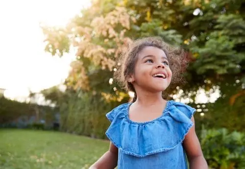 Young Hispanic Girl Having Fun Playing Outdoors In Garden